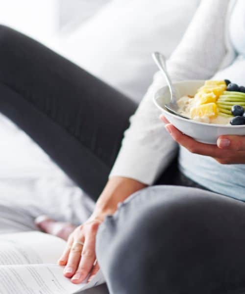 pregnant woman sitting with bowl of fruit and vegetables